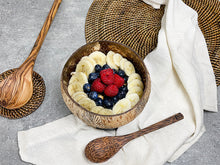 Afbeelding in Gallery-weergave laden, Sfeerbeeld van een Coconut bowl Papu Palm robuust en een kokoshouten lepel met daarin banaan, framboos en blauwe bessen
